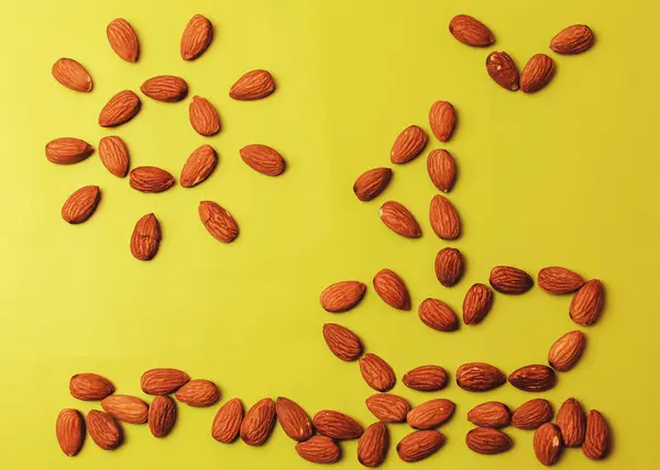 Una gran cantidad de nueces amarillas se exponen sobre un fondo amarillo de papel texturizado en forma de una imagen de verano. El barco, el mar y el sol y la gaviota están dispuestos a partir de almendras . — Foto de Stock