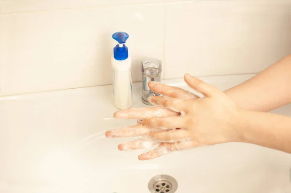 The girl washes her hands in the bathroom after the street during quarantine.prevent the coronavirus pandemic,wash your hands thoroughly with warm water and antibacterial soap.World pandemic concept.