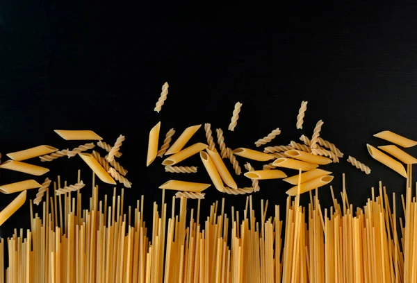 Gele Rauwe Zelfgemaakte Spaghetti Penne Pasta Een Zwarte Betonnen Ondergrond — Stockfoto