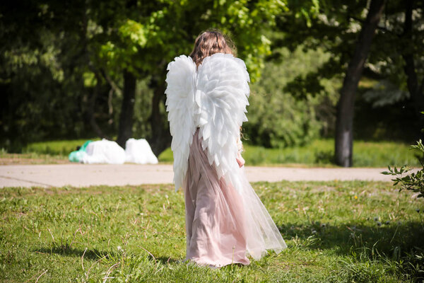 Little angel girl with wings in the park
