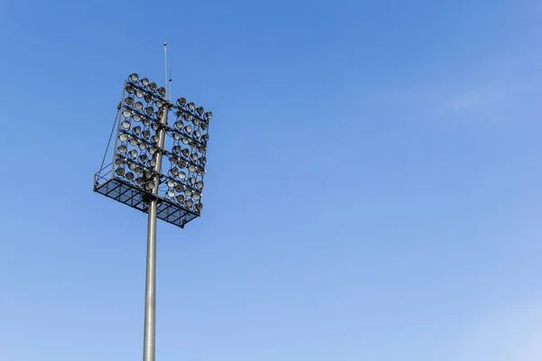 Stadium lighting with a lot of reflectors against blue sky