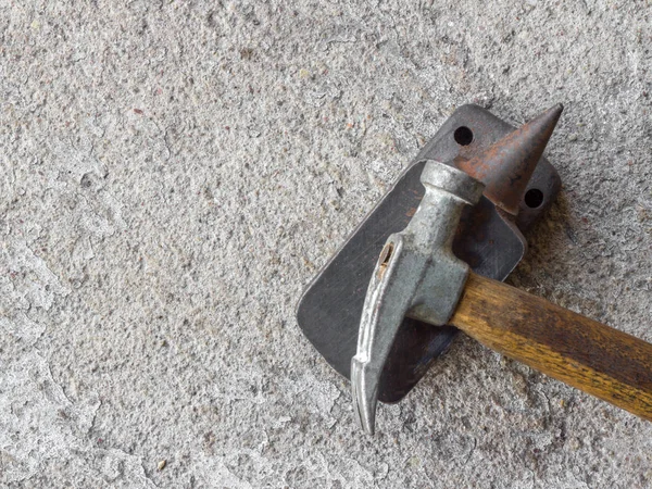 Velho pequeno martelo e bigorna em miniatura com fundo de concreto — Fotografia de Stock
