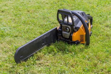 Siyah ve turuncu chainsaw çimenlerin üzerinde