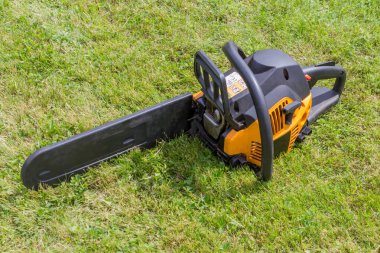 Siyah ve turuncu chainsaw çimenlerin üzerinde