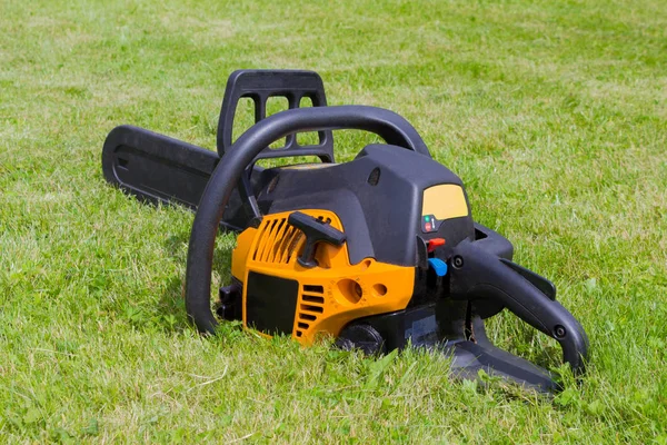 Black and orange chainsaw on grass — Stock Photo, Image