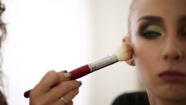 Make-up artiest gaat poeder op het gezicht van de modellen — Stockvideo