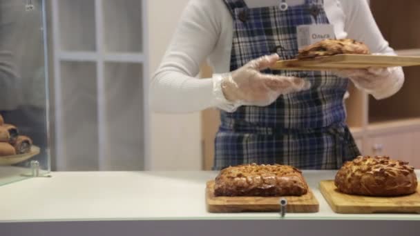 Baker pone pasteles en el escaparate — Vídeo de stock