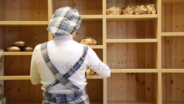 Der Bäcker stellt Brot in die Regale seines Ladens — Stockvideo