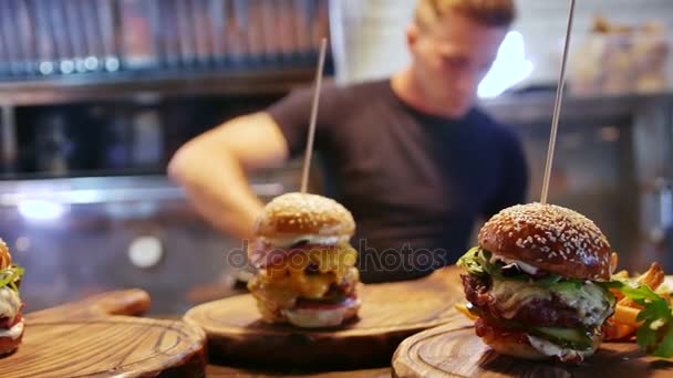 Seorang juru masak muda meletakkan kentang goreng yang lezat di hamburger Amerika — Stok Video