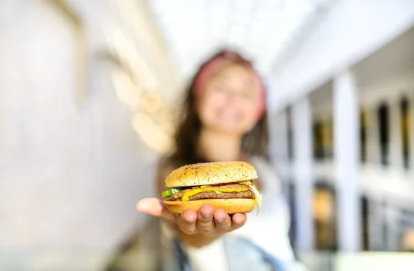 소식통 여자 손바닥에 햄버거를 들고 그의 포획을 제공 합니다. 햄버거에 주요 초점 — 스톡 사진