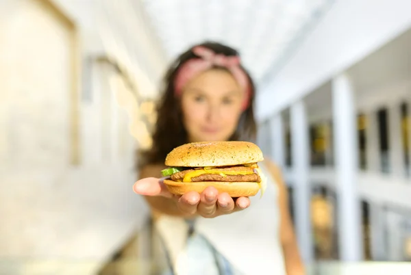 hippi kız hamburger avucunda tutan ve almak onun sunmaktadır. Burger Ana odak