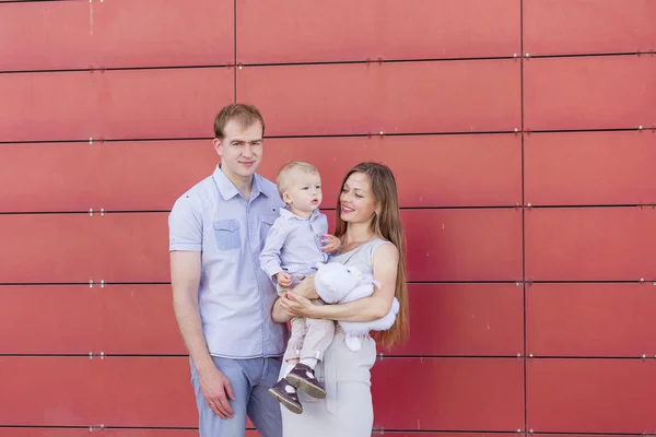 Retrato de una familia joven sobre un fondo rojo — Foto de Stock