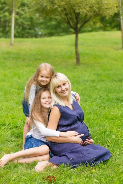 Joven madre embarazada con sus tres hijas en un parque —  Fotos de Stock