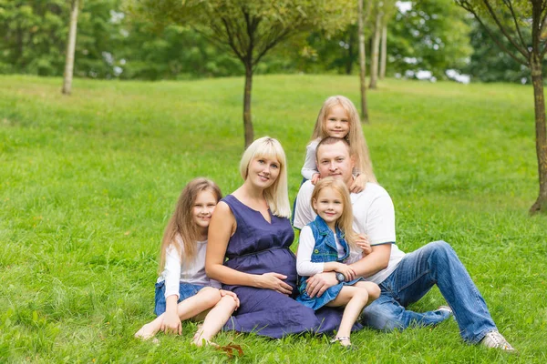 Mladá těhotná matka se svou rodinou v parku — Stock fotografie