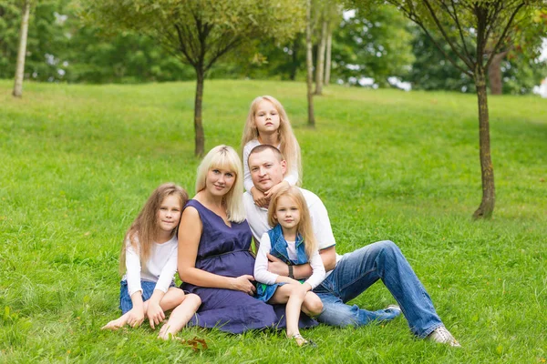 Young pregnant mother with her family in a park — Stock Photo, Image