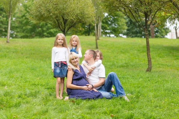 Mladá těhotná matka se svou rodinou v parku — Stock fotografie