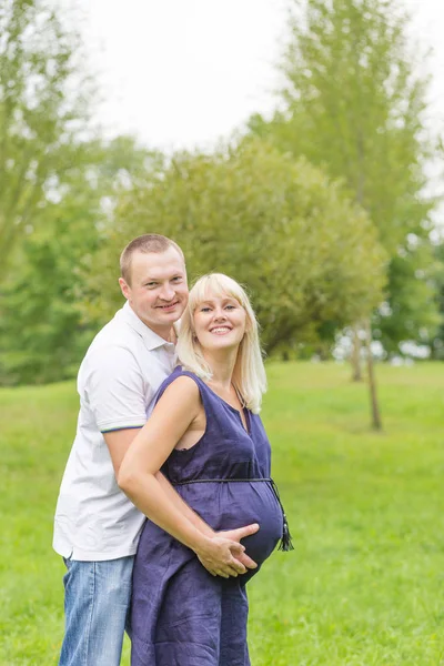 公園で彼女の家族と一緒に妊娠中の若い母親 — ストック写真