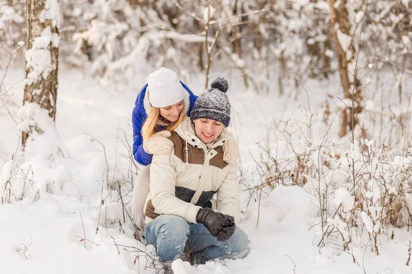 El muchacho y la muchacha descansan en el bosque invernal . — Foto de Stock