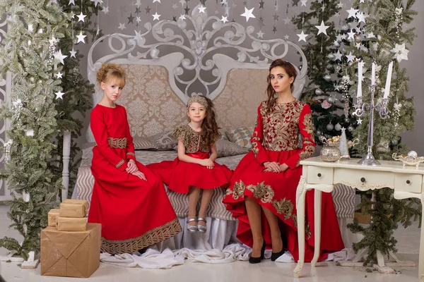 Tre flickor i en röd kväll klä granen. — Stockfoto