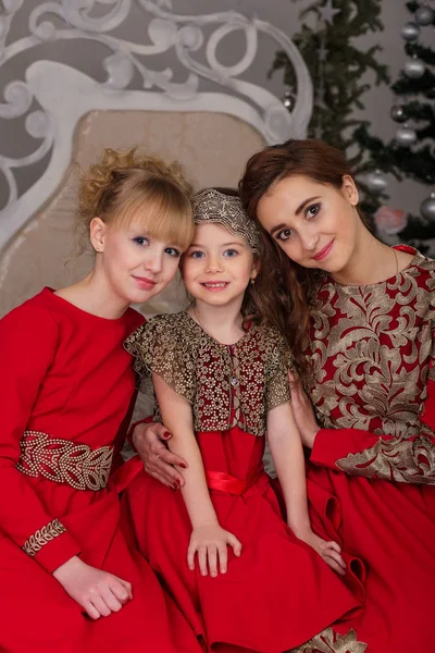 Τρία κορίτσια σε ένα βράδυ κόκκινο φόρεμα το χριστουγεννιάτικο δέντρο. — Φωτογραφία Αρχείου