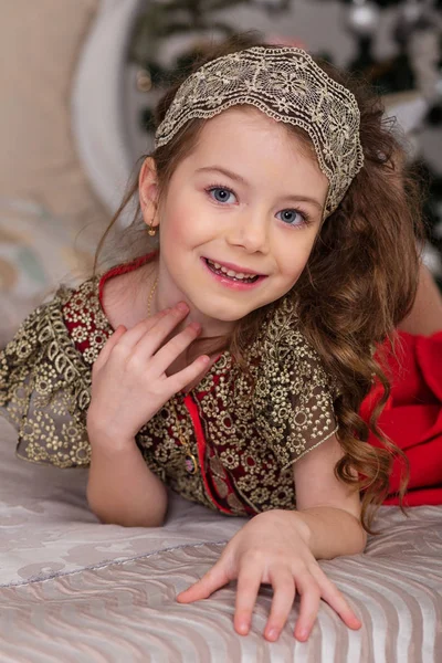 Pequena menina bonita em um vestido de noite vermelho a árvore de Natal . — Fotografia de Stock
