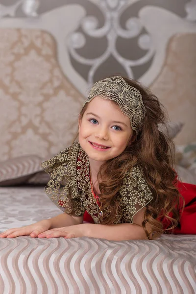 Kleines schönes Mädchen in einem roten Abendkleid den Weihnachtsbaum. — Stockfoto