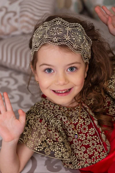 Kleines schönes Mädchen in einem roten Abendkleid den Weihnachtsbaum. — Stockfoto