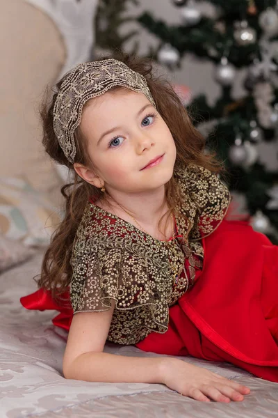 Pequena menina bonita em um vestido de noite vermelho a árvore de Natal . — Fotografia de Stock