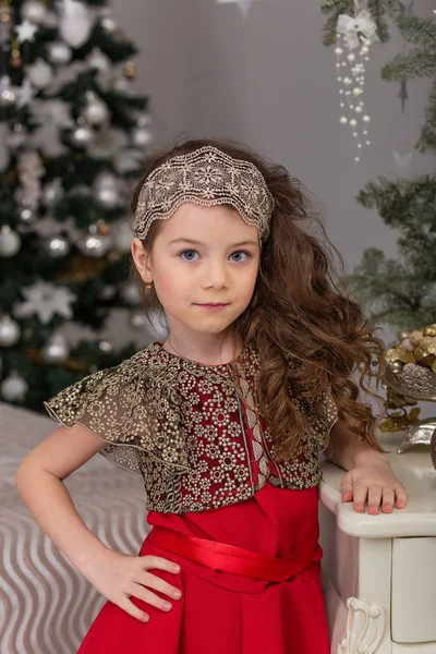 Kleines schönes Mädchen in einem roten Abendkleid den Weihnachtsbaum. — Stockfoto
