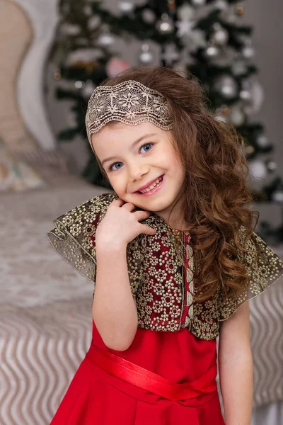 Lilla vackra flicka i en röd frack julgran. — Stockfoto