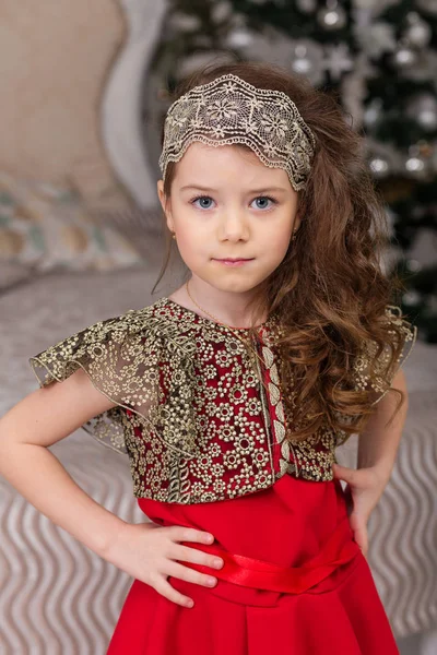 Lilla vackra flicka i en röd frack julgran. — Stockfoto