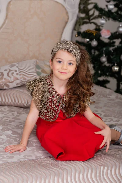 Pequena menina bonita em um vestido de noite vermelho a árvore de Natal . — Fotografia de Stock