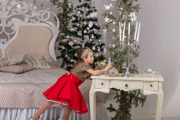 Little beautiful girl in a red evening dress the Christmas tree. — Stock Photo, Image