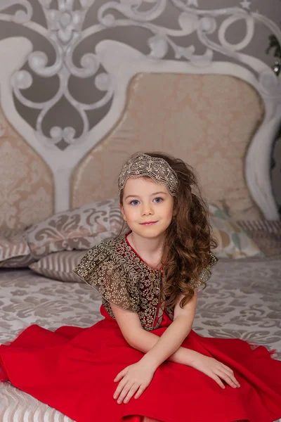 Kleines schönes Mädchen in einem roten Abendkleid den Weihnachtsbaum. — Stockfoto