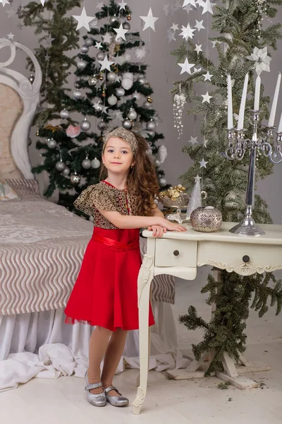 Όμορφο κοριτσάκι σε ένα κόκκινο φόρεμα βράδυ το χριστουγεννιάτικο δέντρο. — Φωτογραφία Αρχείου