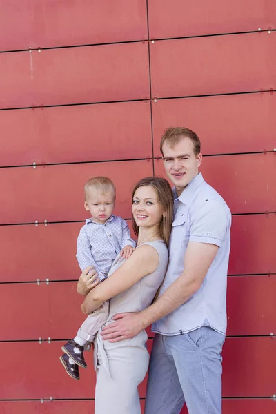 Retrato de una familia joven sobre un fondo rojo — Foto de Stock