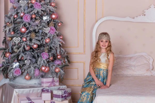 Vacker flicka i en lång aftonklänning i juldekorationer. — Stockfoto