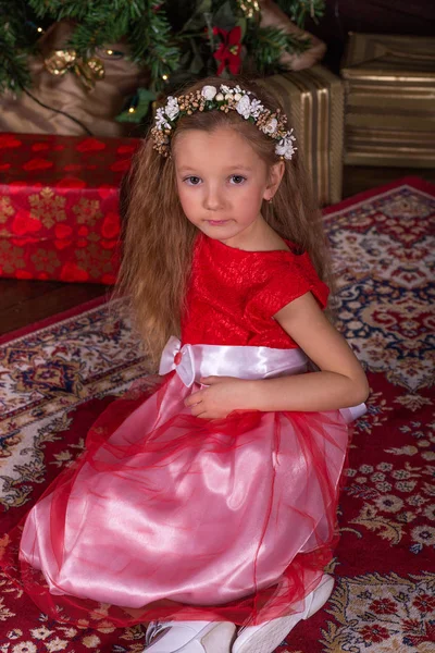 Όμορφο κοριτσάκι σε κόκκινο φόρεμα στο χριστουγεννιάτικο δέντρο. — Φωτογραφία Αρχείου
