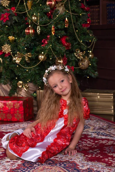 Όμορφο κοριτσάκι σε κόκκινο φόρεμα στο χριστουγεννιάτικο δέντρο. — Φωτογραφία Αρχείου