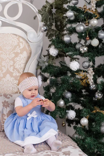 La bambina vestita di blu sul letto dell'albero di Natale — Foto Stock