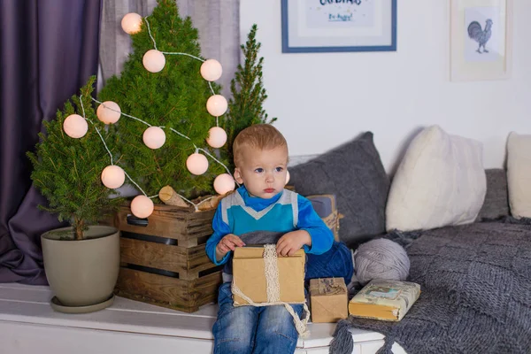 Un bambino si siede vicino all'albero di Natale in previsione della vacanza — Foto Stock