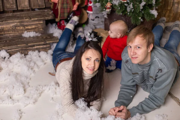 Coppia giovane con un bambino sul pavimento vicino a un albero di Natale — Foto Stock