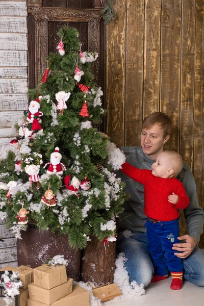 Giovane padre con bambino seduto su un albero di Natale . — Foto Stock