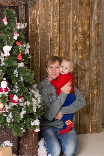 Giovane padre con bambino seduto su un albero di Natale . — Foto Stock