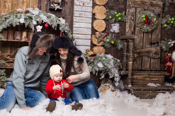 Coppia giovane con bambino in pelliccia seduto su un albero di Natale . — Foto Stock