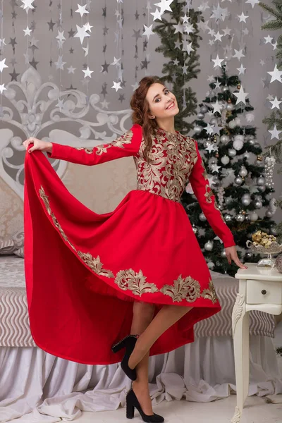 Gyönyörű lány piros hosszú ruha, a karácsonyfa — Stock Fotó