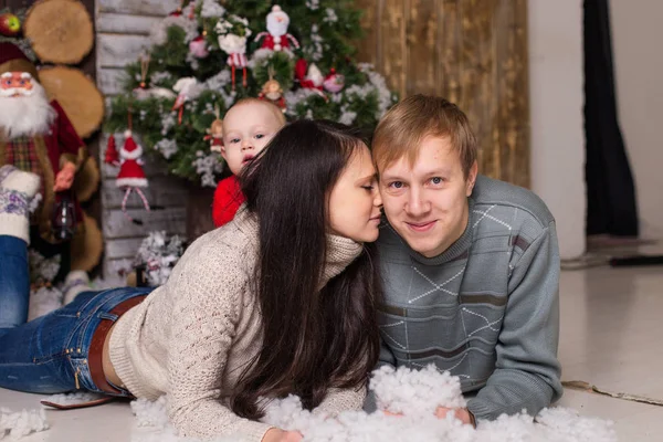Pareja joven con un bebé en el suelo cerca de un árbol de Navidad — Foto de Stock