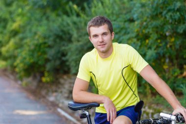 Genç bir adam açık havada bisiklet üzerinde