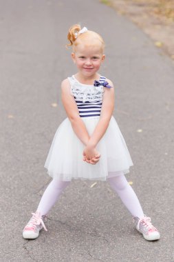 Sevimli küçük bir kız güzel bir elbise ve oynarken spor ayakkabı 