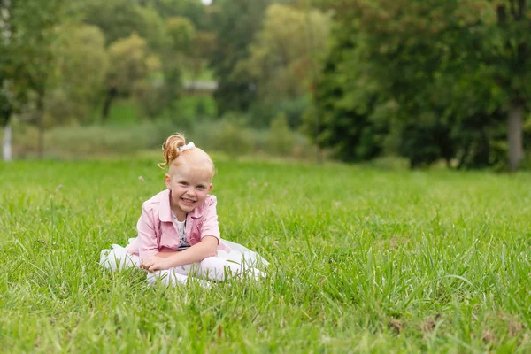 A cute little girl in a beautiful dress and sneakers playing in — Stock Photo, Image